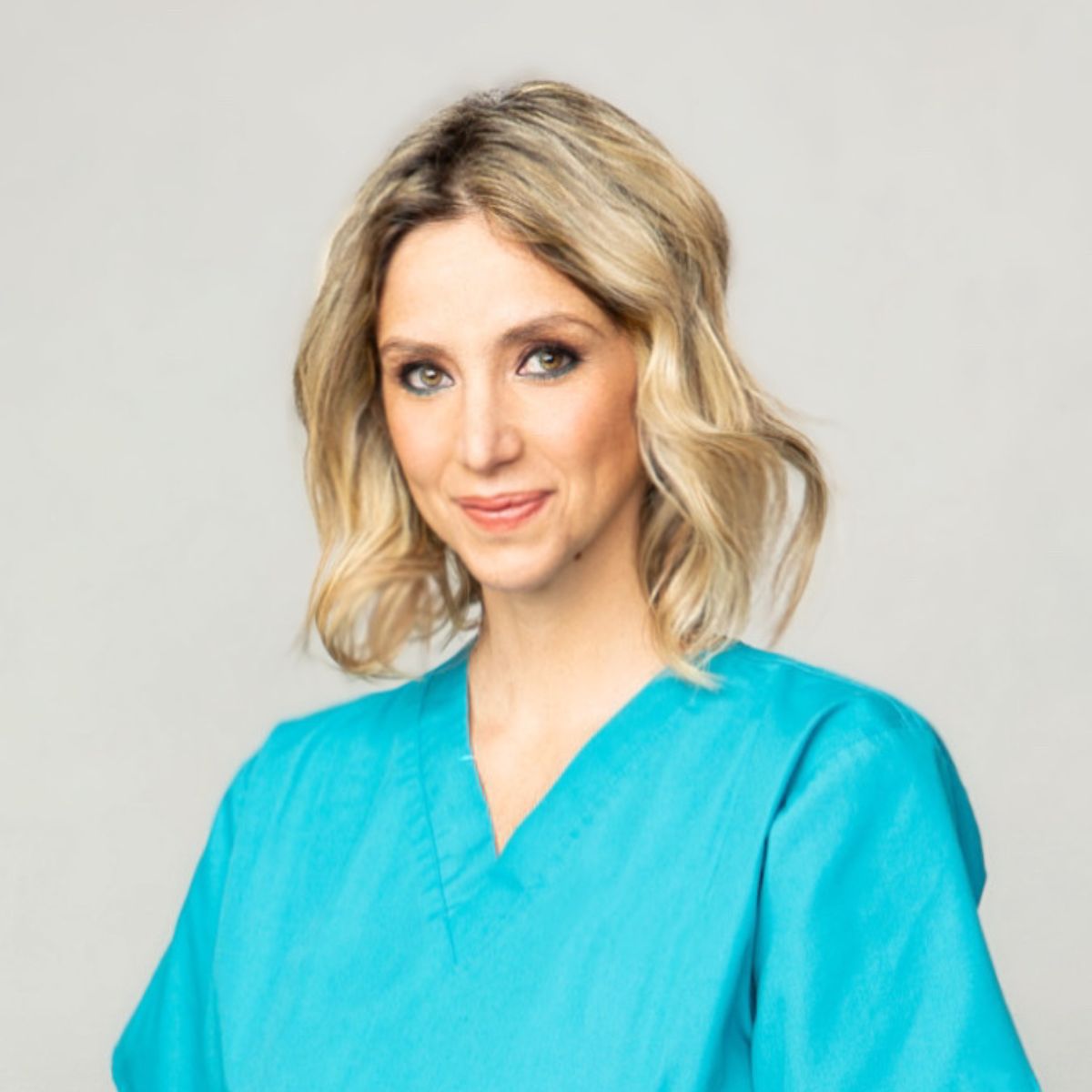 Portrait of Emanuela Lazzaroni-Tealdi, Senior Embryologist and Laboratory Manager, wearing a turquoise uniform and smiling confidently.