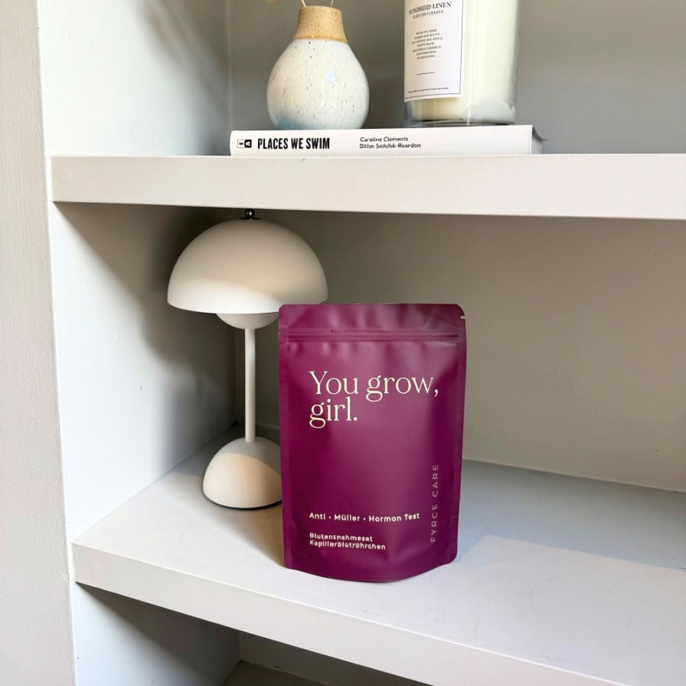Fyrce Care AMH-Test-Beutel in einem hellen Regal neben Vase, Lampe und Kerze