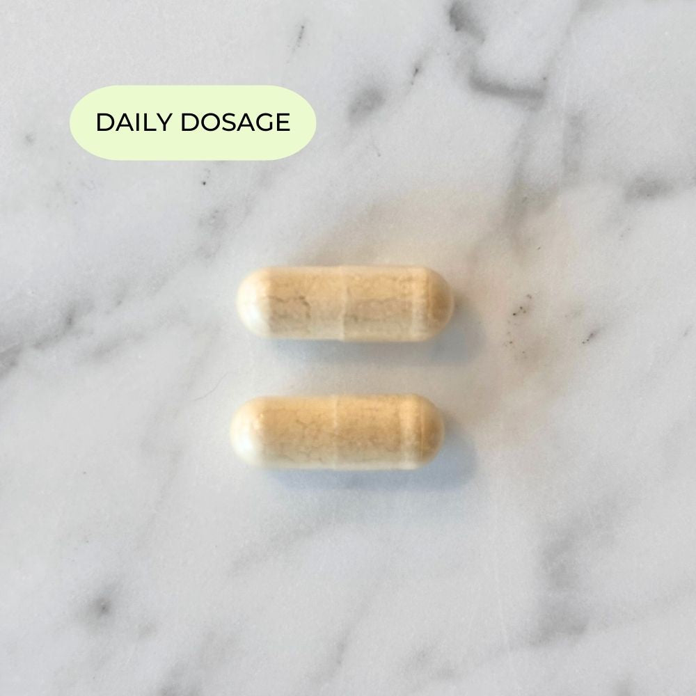 Daily dosage of Her Fertility supplement shown with two capsules on marble background.