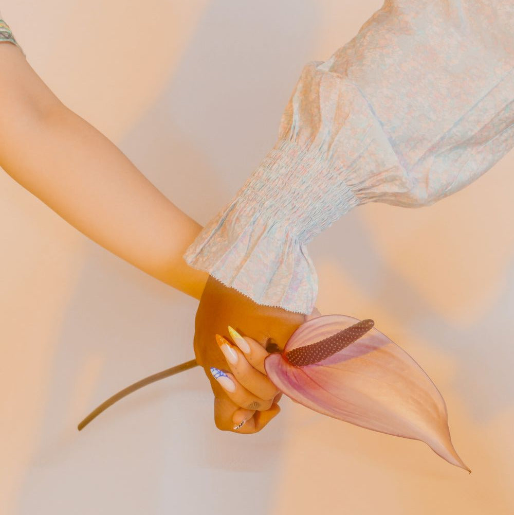 Close-up of two women holding hands with a flower, symbolizing support and care, by Fyrce Care