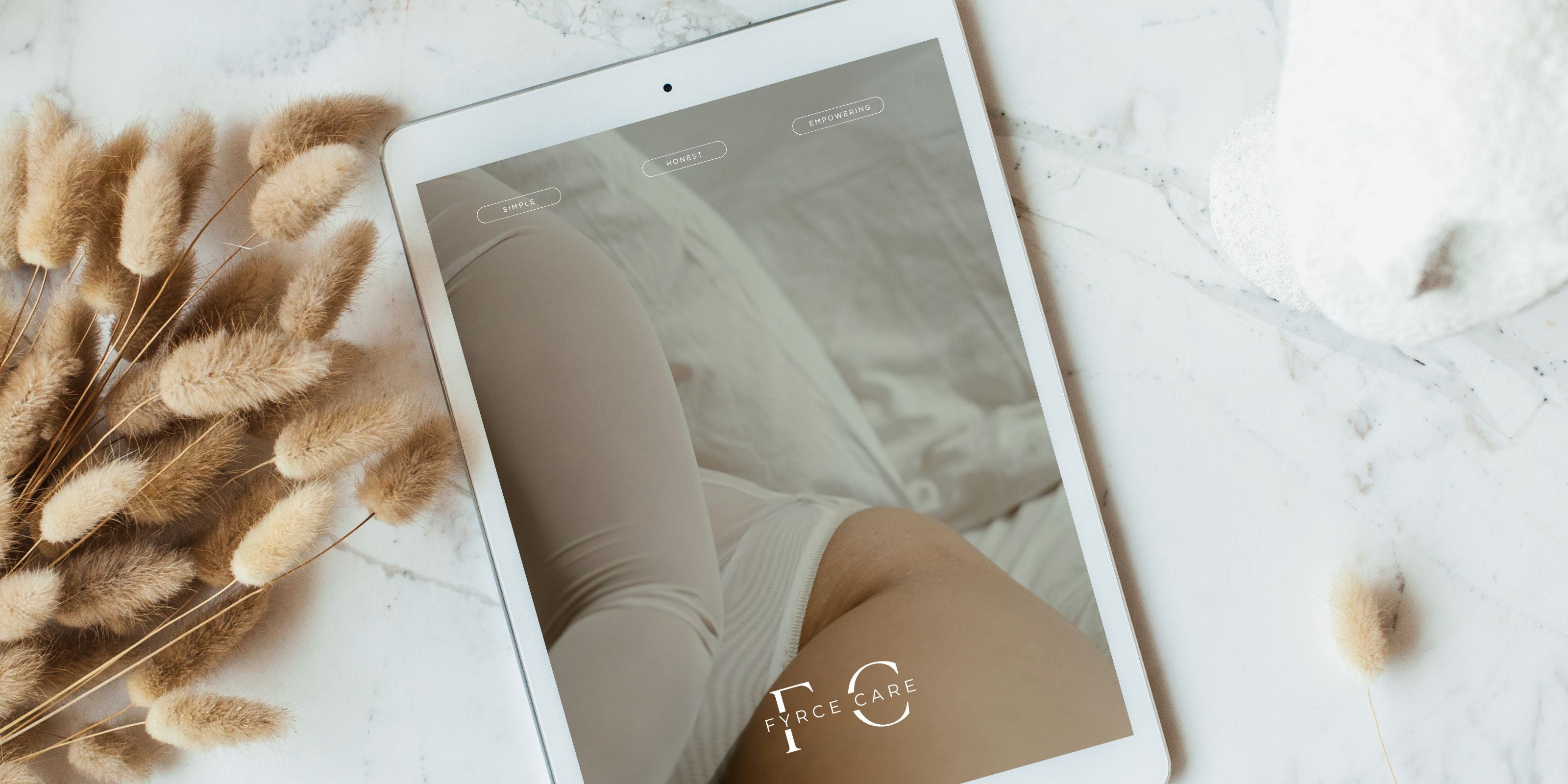 Tablet mit Pampasgras im Hintergrund, zeigt den Text: Dein Ratgeber fürs Eizellen Einfrieren – Fordere deinen kostenlosen Ratgeber an.