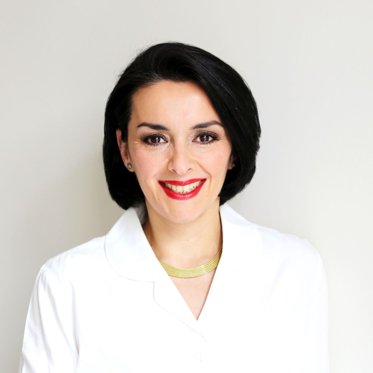 Portrait of Dr. Gülden Halis, a leading fertility specialist and founder of Kinderwunschteam Berlin, smiling confidently in a white coat.