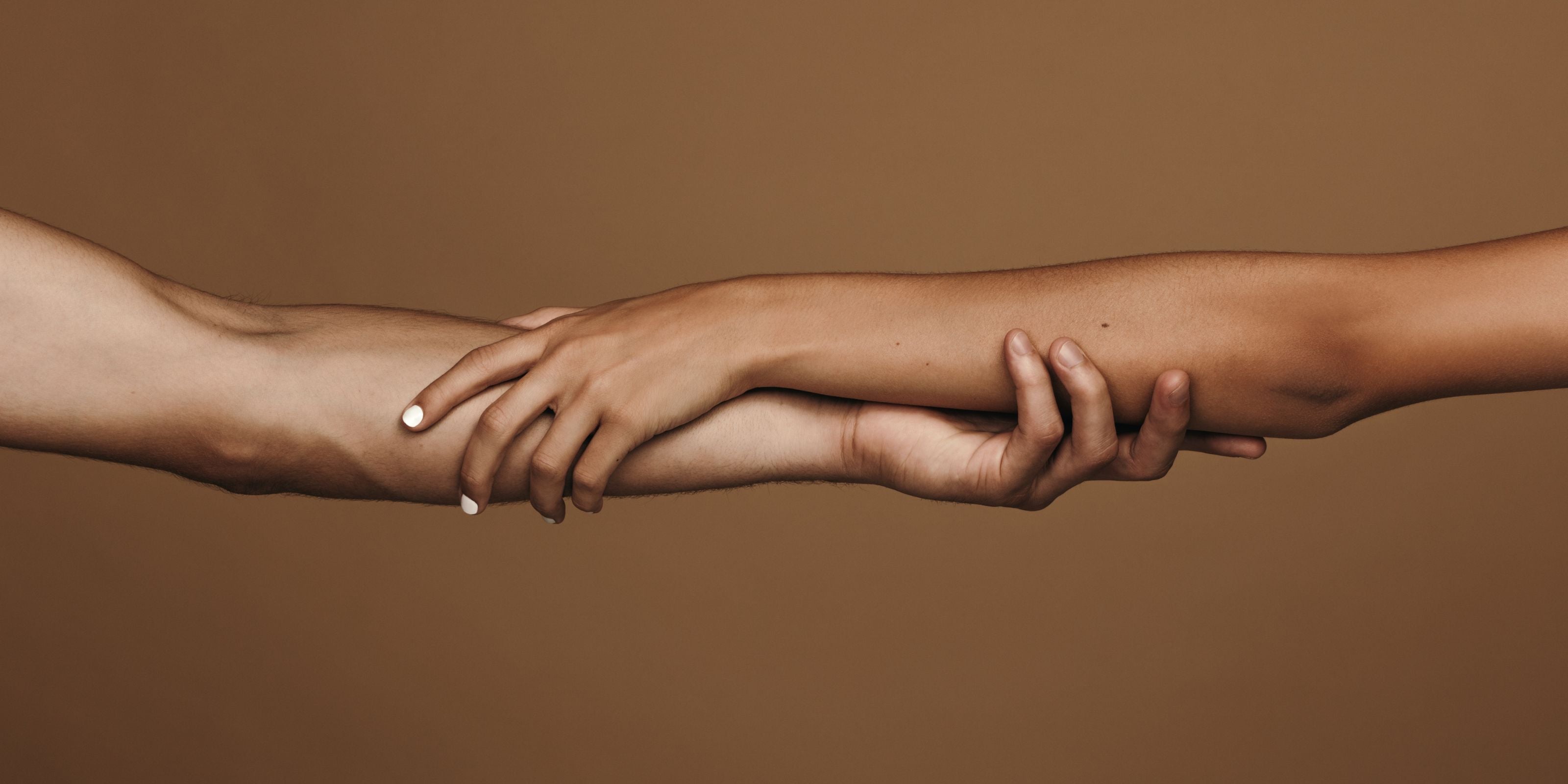 Close-up of hands touching against a brown background, symbolizing connection and unity, by Fyrce Care