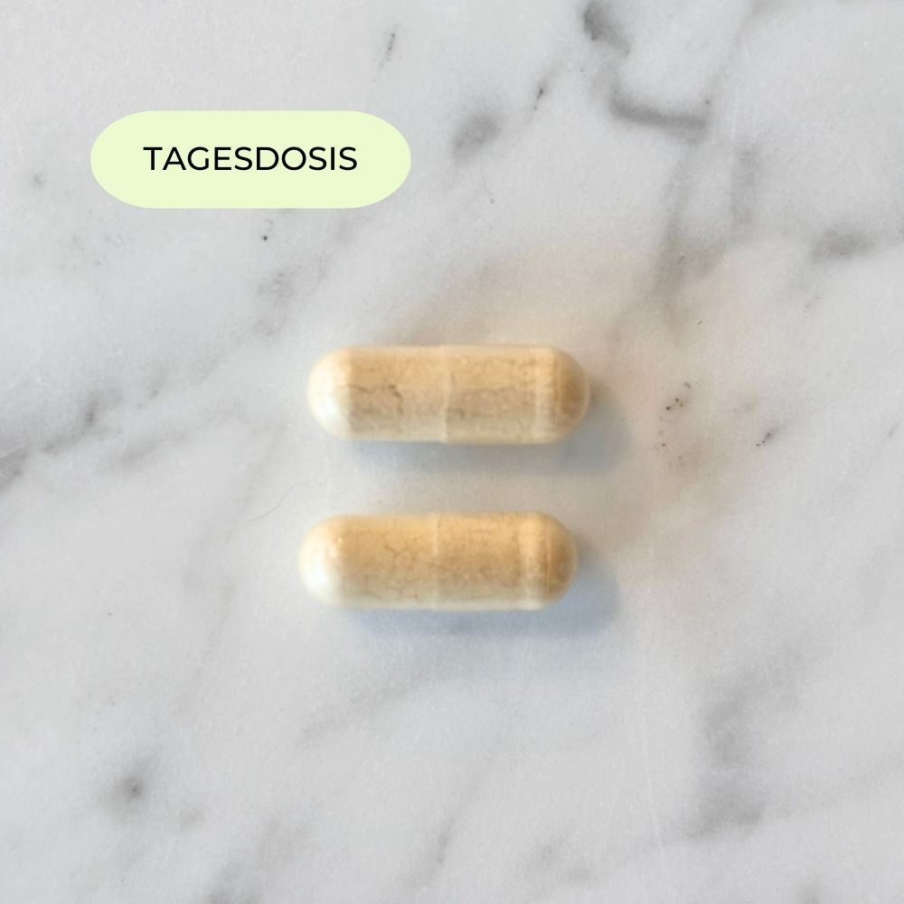 Tagesdosis des Her Fertility Supplements mit zwei Kapseln auf Marmoroberfläche.