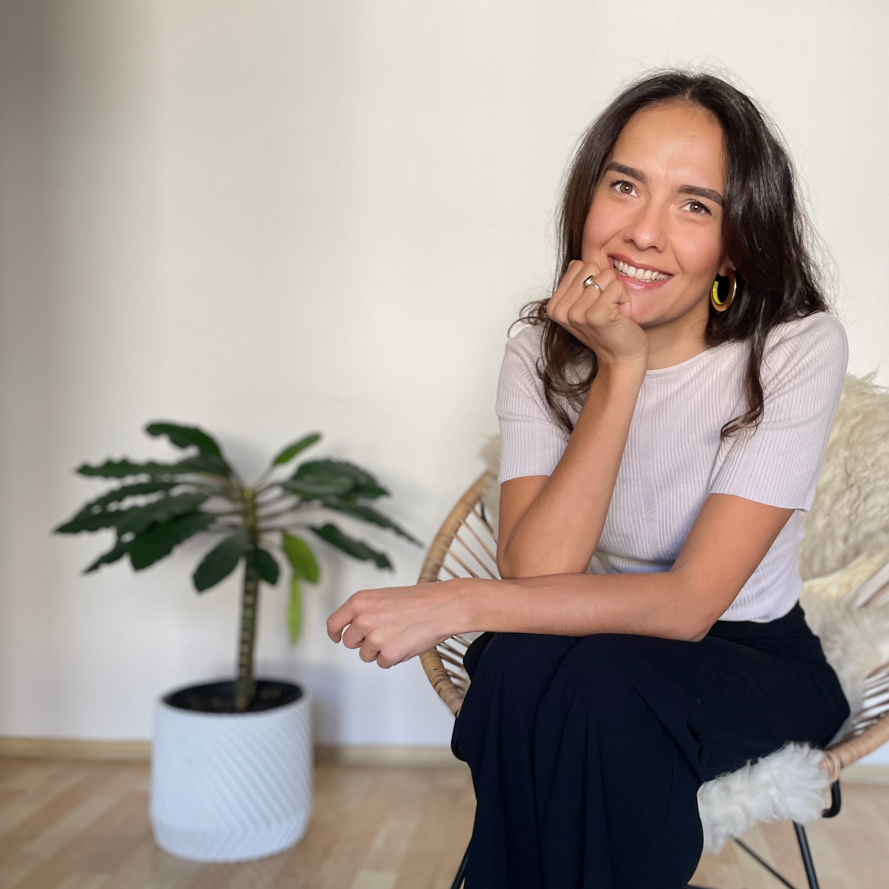 Lisa Ladner, co-founder of Fyrce Care, sitting next to a palm in a relaxing chair, smiling warmly