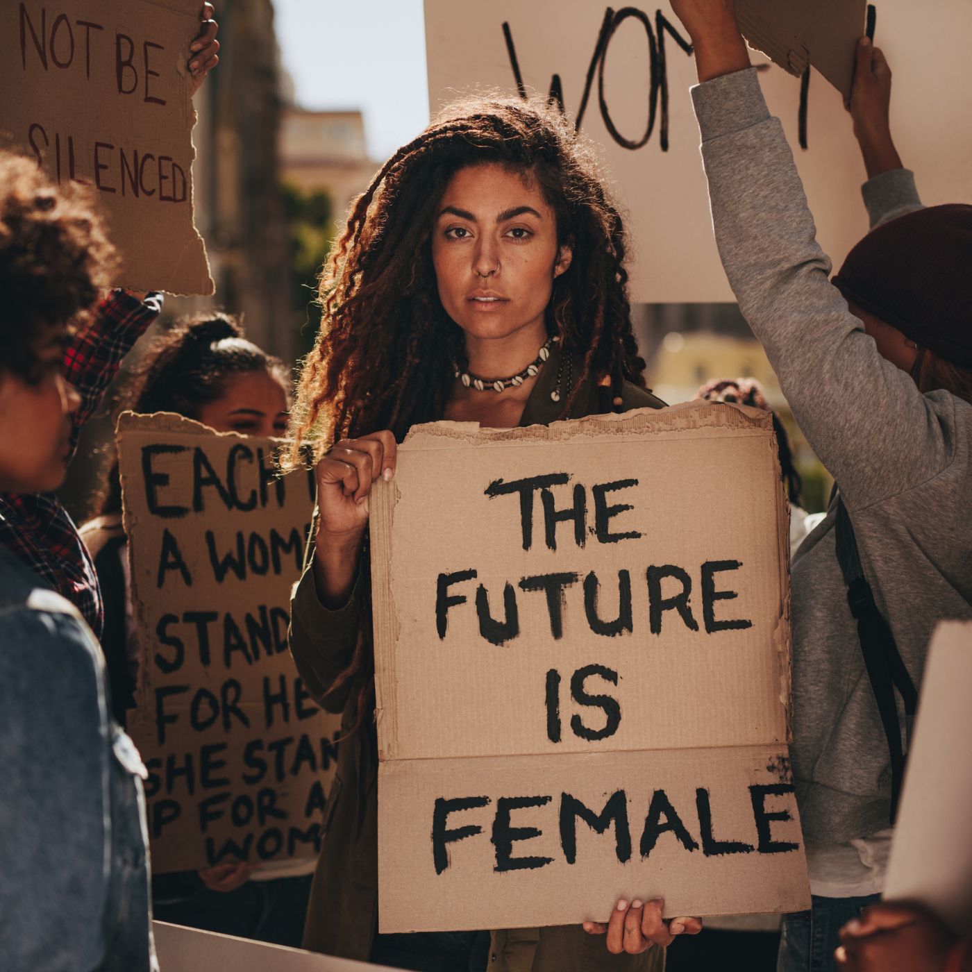 A diverse group of women holding protest signs with messages of female empowerment, including "The Future is Female."