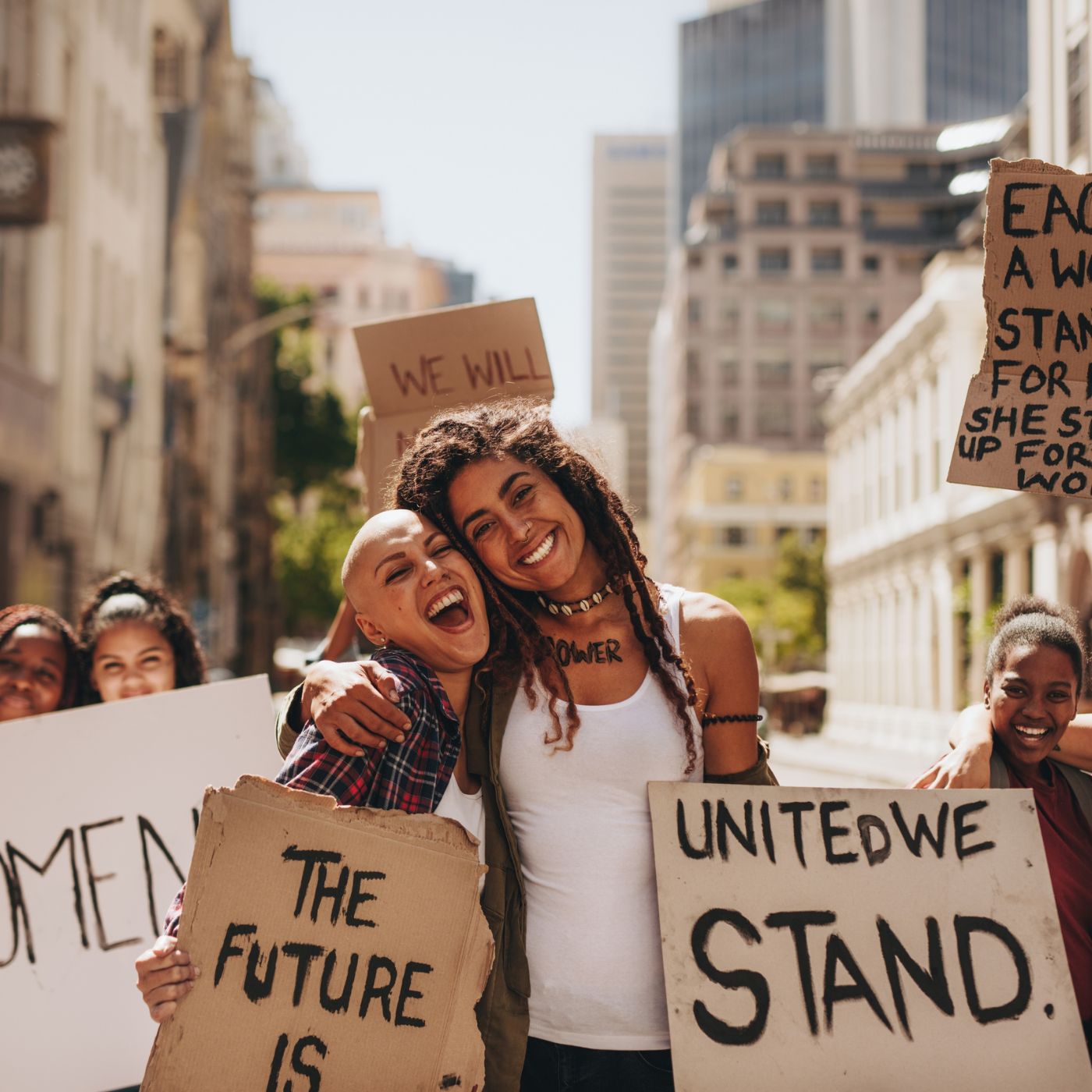 Group of diverse women at a protest holding signs that read "The Future is Female" and "United We Stand," celebrating female empowerment.