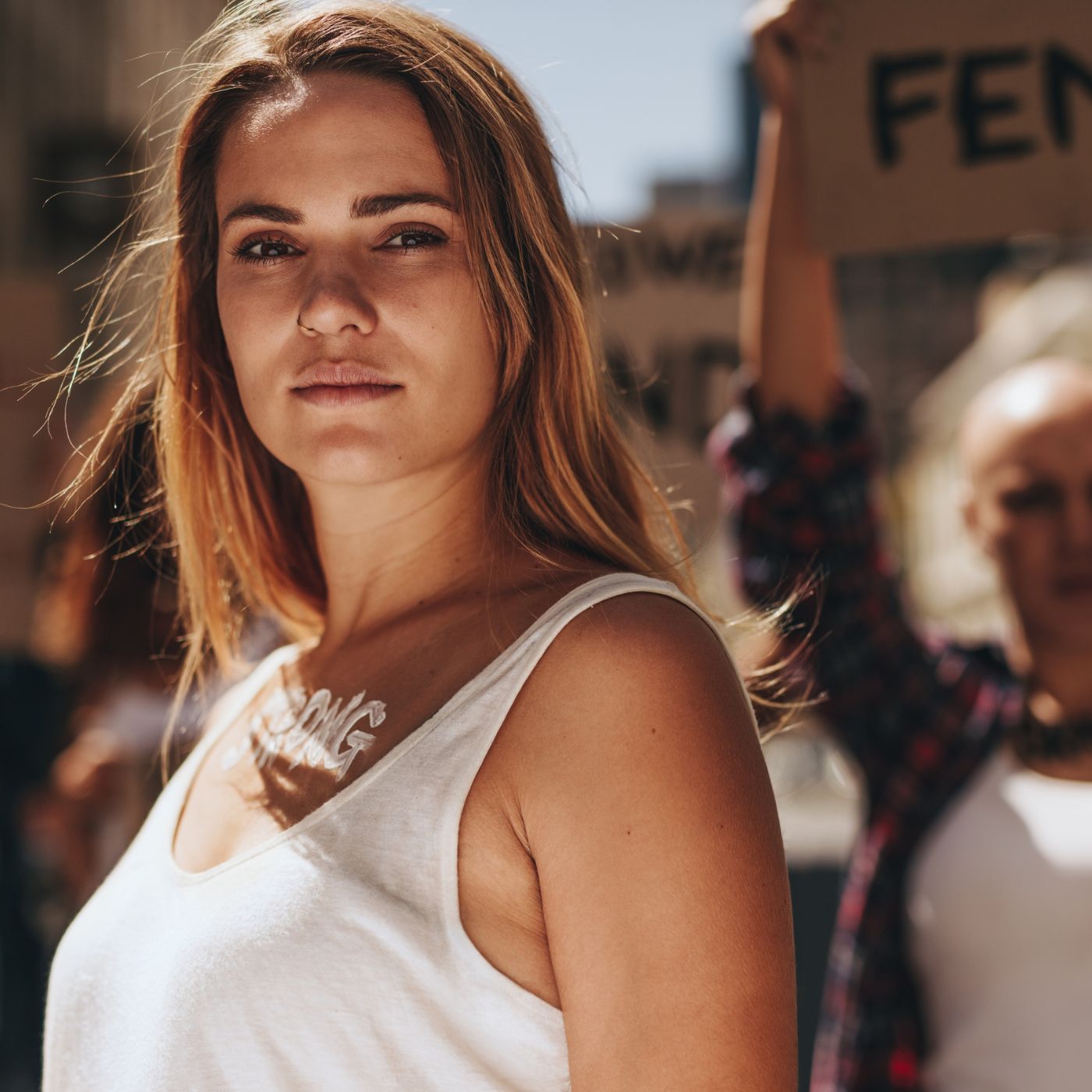 Close-up of a woman at an empowerment protest, with signs advocating for female rights in the background.